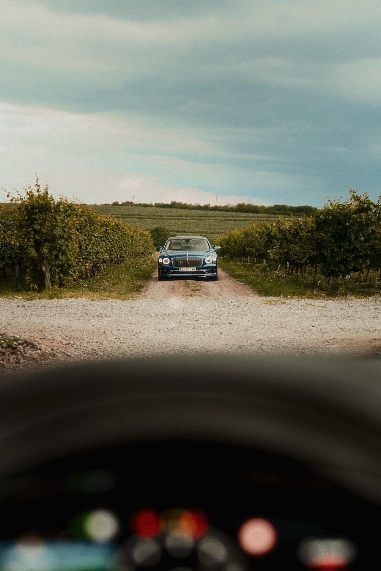 Bentley Flying Spur seen through a windshield on a vineyard road near Issa Resort